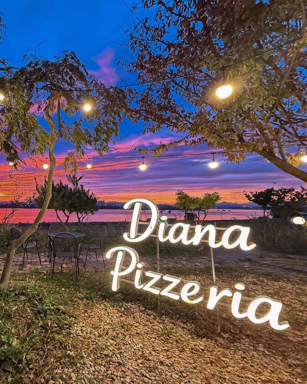 밤이 내린 강변 정원에 불을 밝힌 Diana Pizzeria 사인